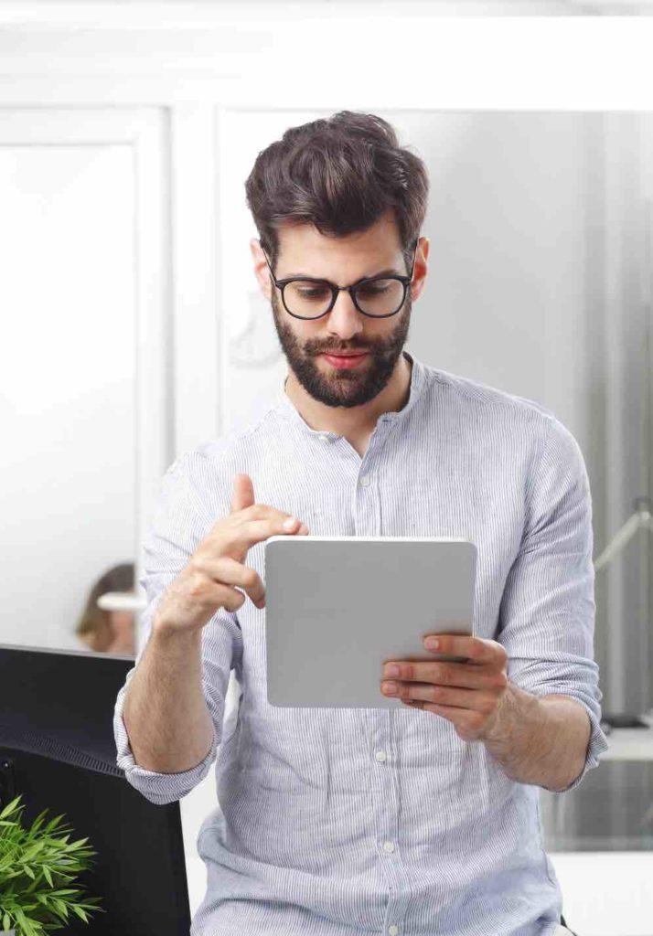 Junger Mann schaut am iPad nach Schadenersatzansprüchen