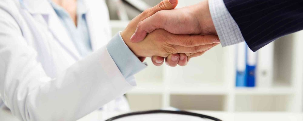 Ärztin reicht einem Patienten die Hand